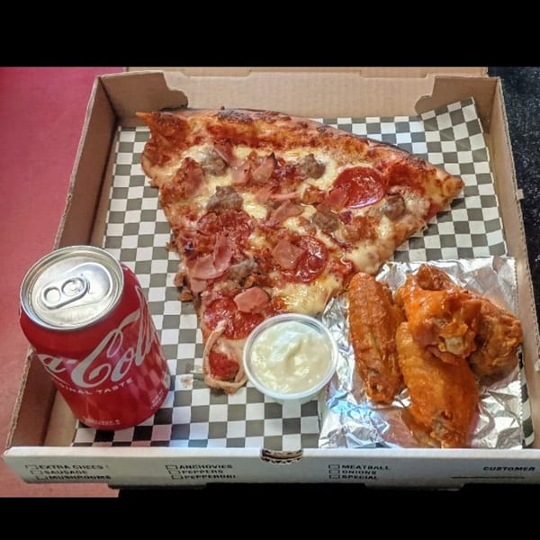 A Checkers Pizza box with a slice of meat pizza, chicken wings, dipping sauce, and a Coke.