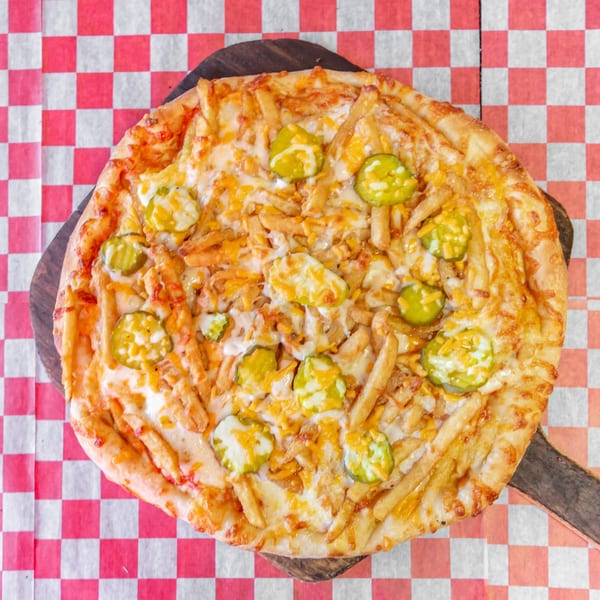 Checkers Pizza's unique pizza with french fries, pickles, and melted cheese on a checkered tablecloth.