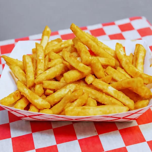 A white paper tray filled with golden-brown french fries, resting on a red and white checkered tablecloth.